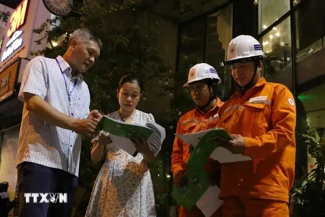 Des représentants de la compagnie d'électricité Gia Dinh demandent aux habitants et aux ménages d'affaires de la rue Dien Bien Phu (arrondissement de Binh Thanh, Hô Chi Minh-Ville) d'éteindre ou de réduire la capacité du système d'éclairage de 50 %. Photo: VNA