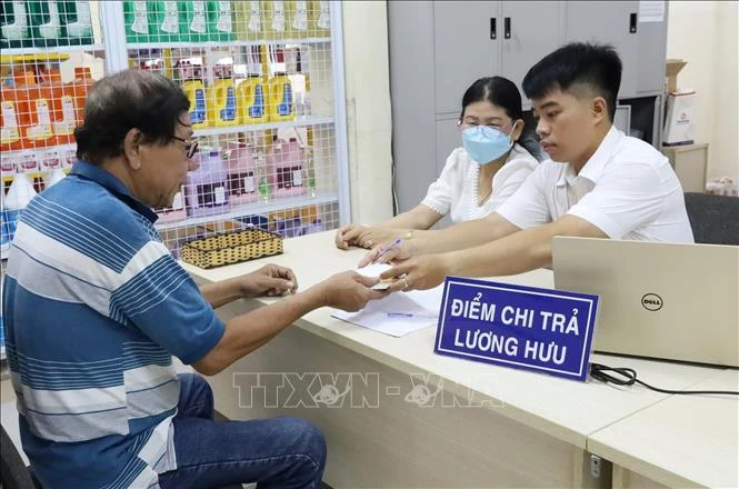 Une personne âgée d'Hô Chi Minh-Ville reçoit une pension dans un bureau de poste. Photo : VNA