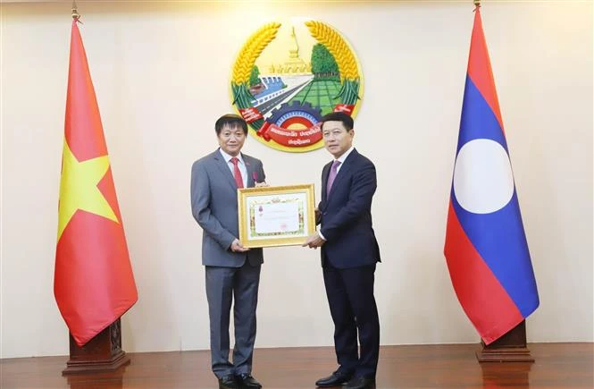 Le vice-Premier ministre et ministre des Affaires étrangères du Laos, Saleumxay Kommasith (droite), remet la noble distinction à l'ambassadeur Nguyen Ba Hung. Photo : VNA