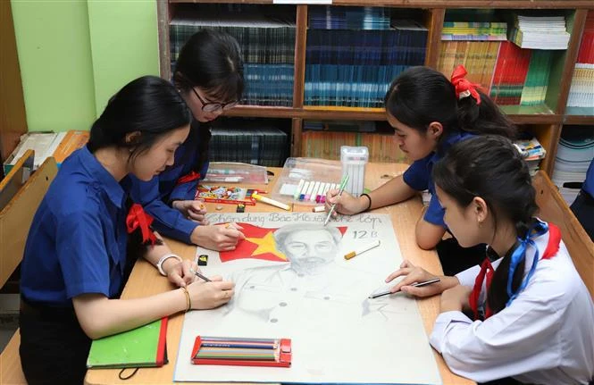 Des élèves de l'école bilingue lao-vietnamienne Nguyen Du dessinent un tableau sur l'Oncle Hô. Photo : VNA