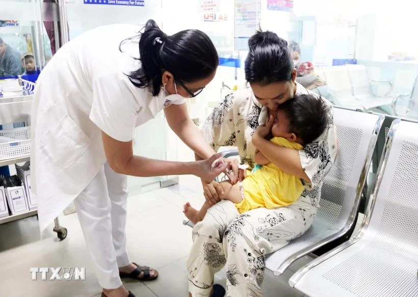 Un agent de santé injectant un vaccin à un enfant. Photo : Vietnam+