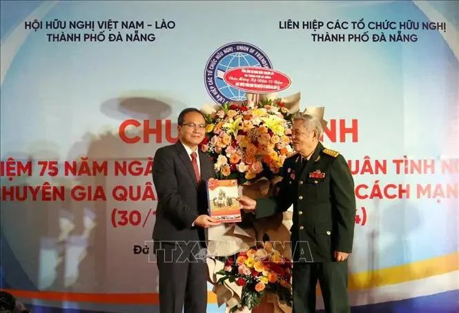 Un représentant du Comité de liaison des volontaires et experts militaires vietnamiens (à droite) offre un annuaire du 75e anniversaire anniversaire de la Journée traditionnelle des soldats volontaires et experts vietnamiens au Lao au consul général du Laos à Da Nang. Photo : VNA