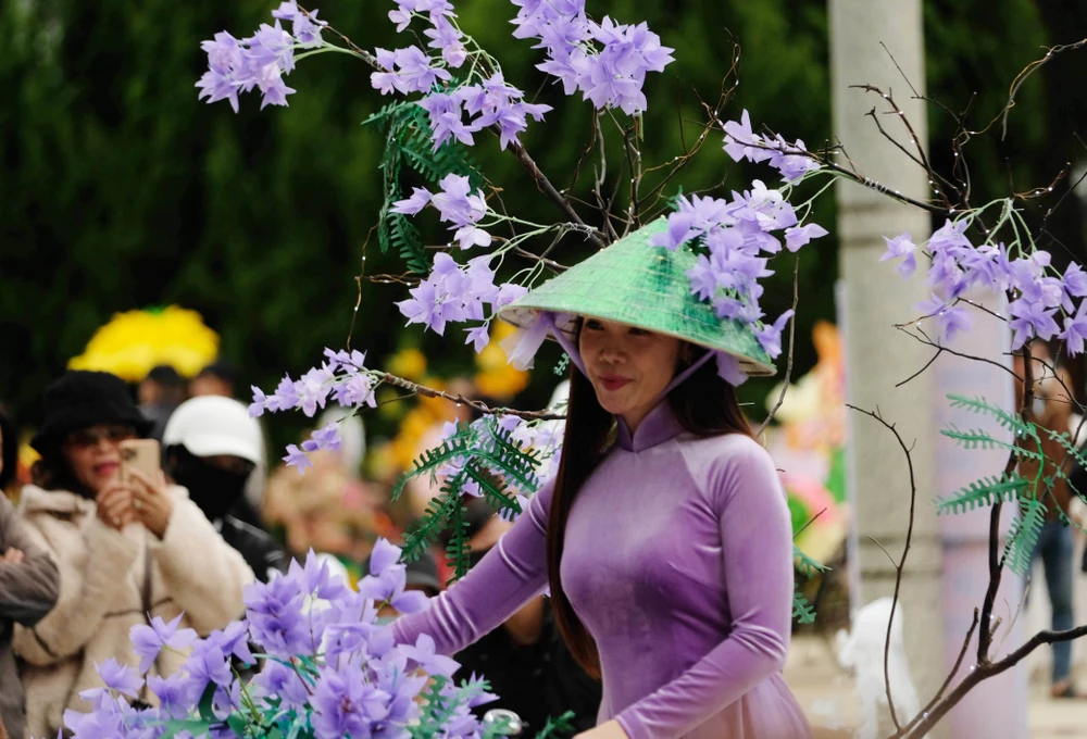 Une charmante enseignante avec des fleurs de poinciana violettes en papier combinées à un chapeau conique et un ao dai. Photo : Nguyen Dung – VNA