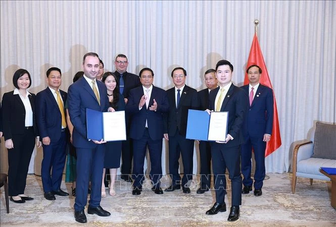 Le Premier ministre Pham Minh Chinh (centre) assiste à la remise du protocole d'accord sur la recherche d'investissement dans le projet de complexe sportif et de centre commercial à Dong Anh entre T&T du Vietnam et JTA International Holding. Photo : VNA