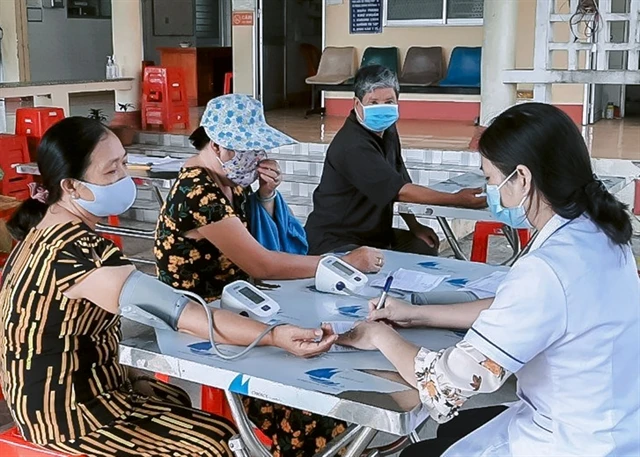Medical staff member checks blood pressure for people in Long An province. (Photo: baolongan.vn)