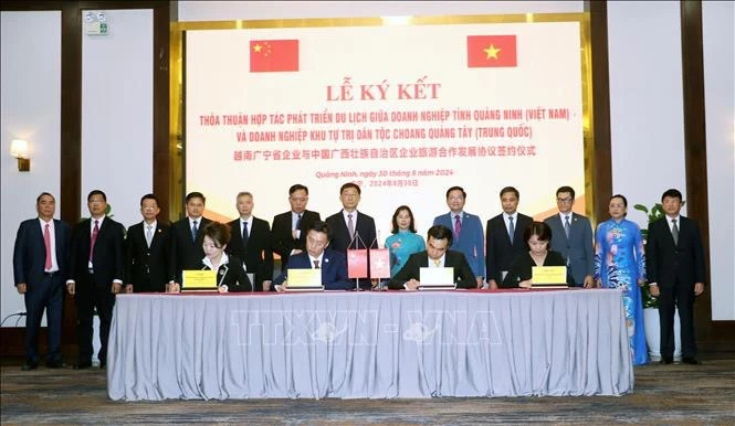 Representatives from Quang Ninh and Guangxi Zhuang Autonomous Region witness the signing of a tourism development cooperation agreement between the two localities' enterprises. (Photo: VNA)