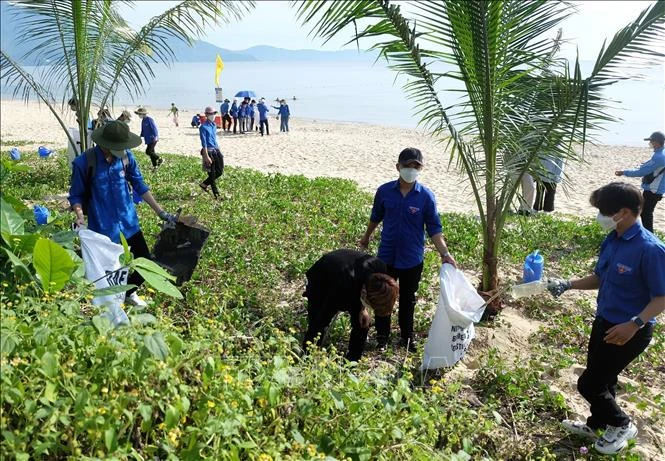 Collecting waste on a beach in the central region. (Photo: VNA)