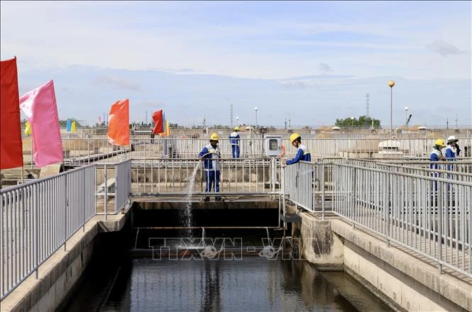 Workers spray water to clean the filtration tank and remove debris at the Binh Hung wastewater treatment plant in HCM City. (Photo: VNA)