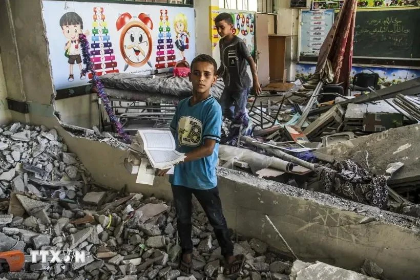 Niños junto a las ruinas de una escuela afectada por un ataque aéreo israelí en la ciudad de Gaza el 25 de junio. (Foto: Xinhua/VNA)