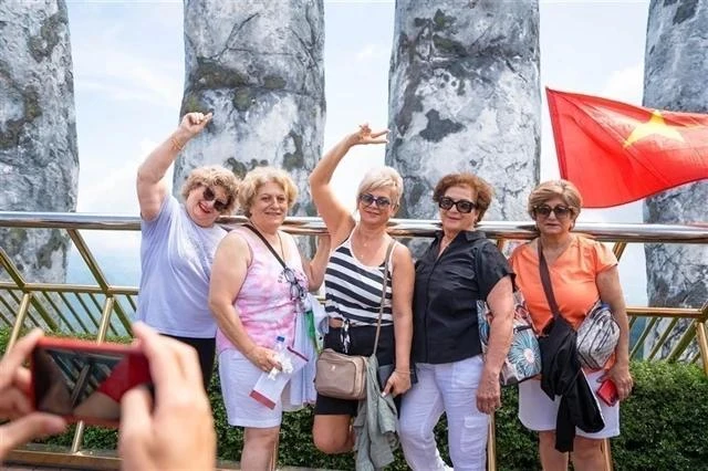 Los turistas extranjeros posan para una foto en el mundialmente famoso Puente Dorado dentro del complejo Sun World de Ba Na Hills en la ciudad de Da Nang (Foto: VNA)