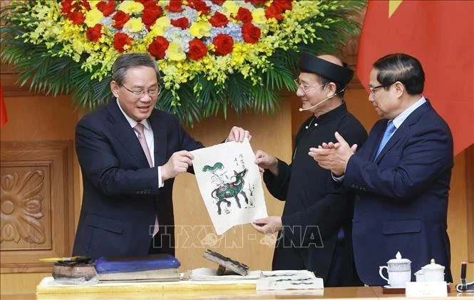 El primer ministro vietnamita, Pham Minh Chinh (derecha), y su par chino, Li Qiang, experimentaron de primera mano la creación de una pintura popular de la etnia Dong Ho. (Foto: VNA)