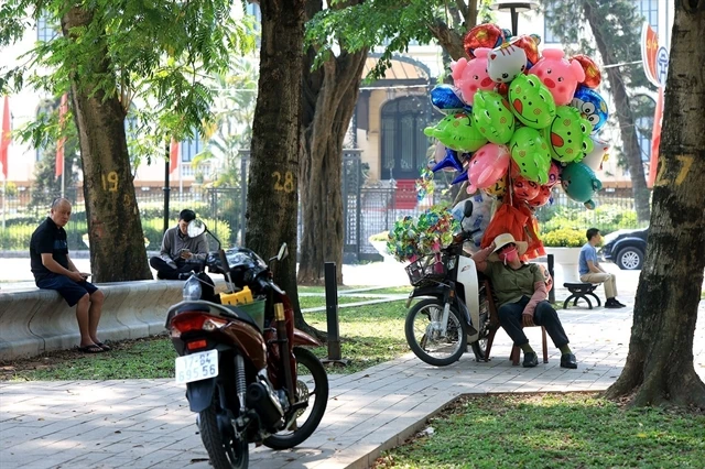 Street vendors in Hanoi make use of any shade to take a rest. (Photo: VNA)