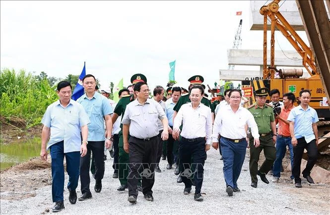 Prime Minister Pham Minh Chinh (second from left) and officials examine the construction site at Highway 61C intersection in Hau Giang Province’s Phung Hiep district on July 13 (Photo: VNA)