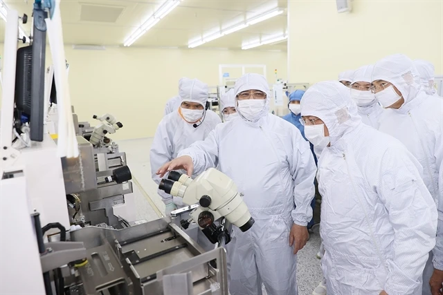 Prime Minister Pham Minh Chinh (centre) visits the semiconductor chip production line of the Hana Micro Vina Co Ltd in the Van Trung Industrial Zone in Bac Giang province. (Photo: VNA)