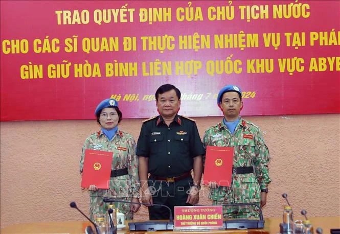 Deputy Minister of National Defence Senior Lieutenant General Hoang Xuan Chien (right) hands over the President's decision to two officers (Photo: VNA)