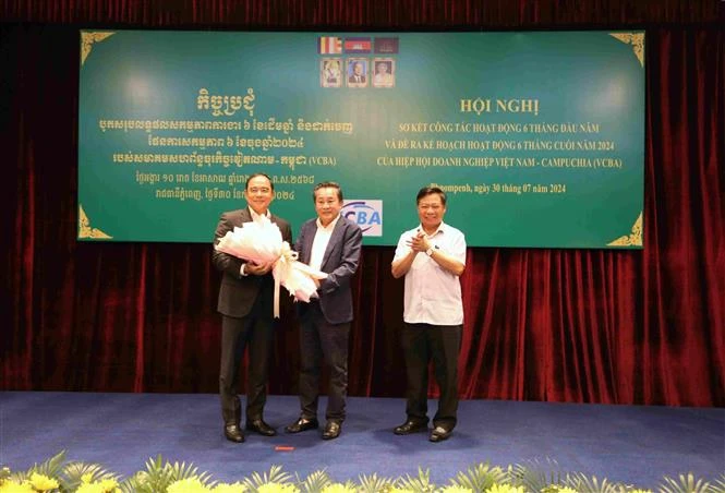 VCBA President Oknha Leng Rithy ( centre) gives flowers to the association’s senior advisor Ly Thuch, who is also Senior Minister and the First Vice President of the Cambodian Mine Action and Victim Assistance Authority at the conference. (Photo: VNA)