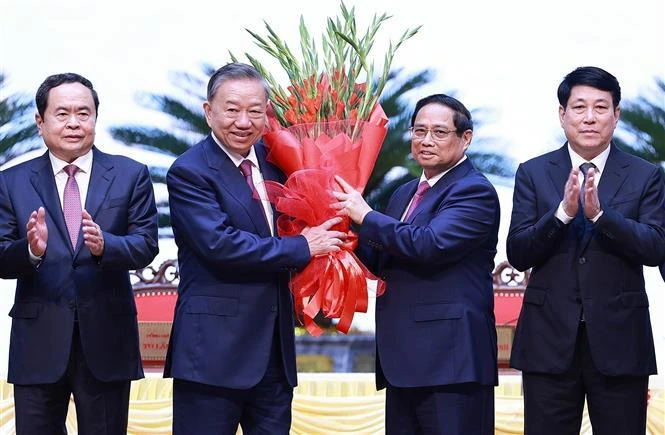 Politburo member and Prime Minister Pham Minh Chinh, on behalf of key and high-ranking leaders of the Party and State, presents flowers to congratulate Party General Secretary To Lam. (Photo: VNA)