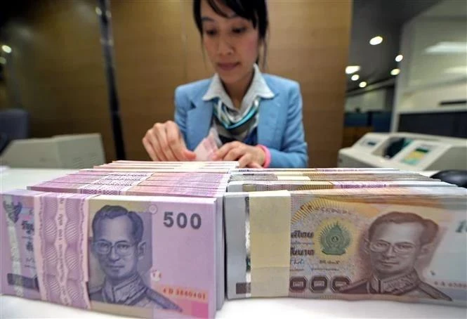 A bank employee counts Thai baht notes in Bangkok, Thailand (Photo: AFP/VNA)