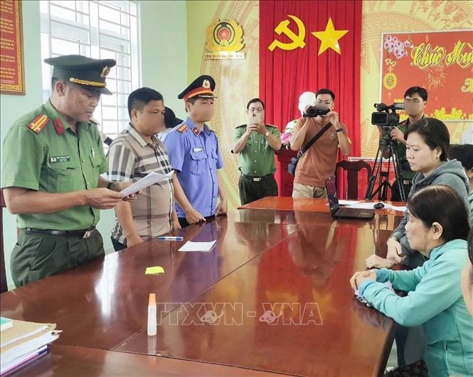 Tran Thi Hong Duyen and Bui Thi Anh Ngoc listen to their arrest warrant at the police station. (Photo: VNA)