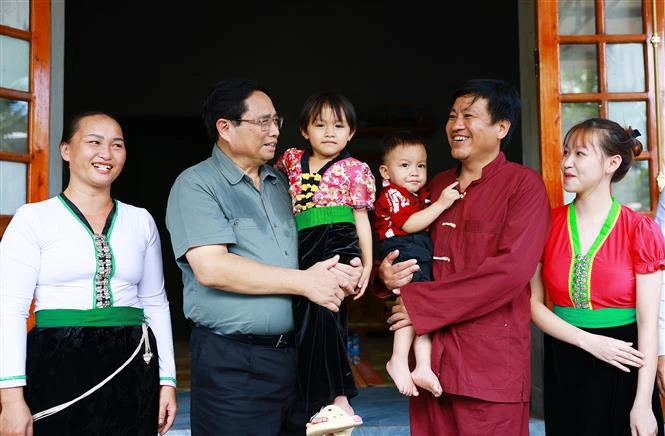 Prime Minister Pham Minh Chinh (2nd from left) visits the family of Xa Van Vong (2nd from right) in Son Phu hamlet, Cao Son commune, Da Bac district, Hoa Binh province, who recently moved into new homes as part of the temporary housing eradication initiative. (Photo: VNA)