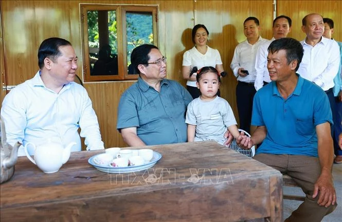 Prime Minister Pham Minh Chinh (second, left) visits a family benefited from the movement to build and repair houses for the needy in Hien Luong commune in Da Bac district of Hoa Binh province. (Photo: VNA)