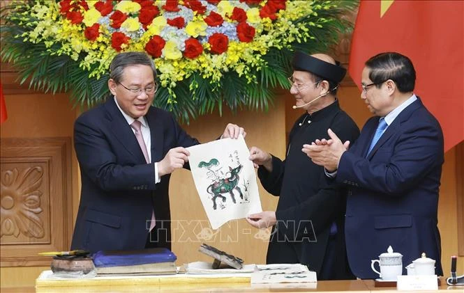 Vietnamese Prime Minister Pham Minh Chinh (R) and Chinese Premier Li Qiang got hands-on experience of making a Dong Ho folk painting. (Photo: VNA)