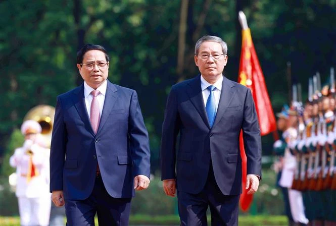 Prime Minister Pham Minh Chinh and Chinese Premier Li Qiang (R) review the guard of honour of the People's Army of Vietnam. (Photo: VNA)