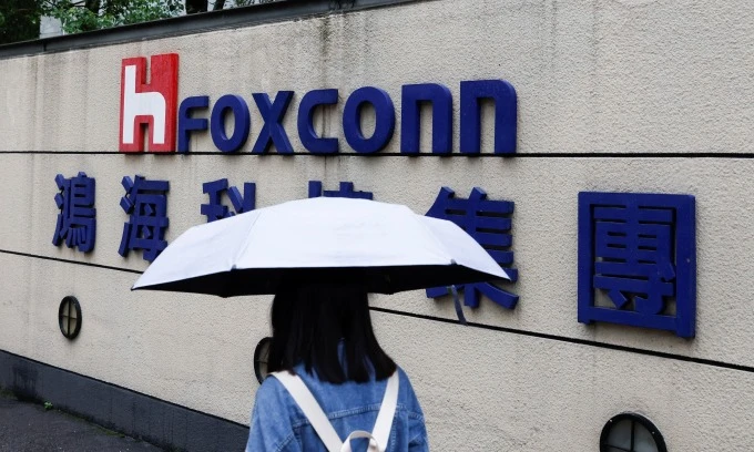 A woman carrying an umbrella walks past the logo of Foxconn outside a company's building in Taipei, Taiwan, Oct. 31, 2022. (Photo: Reuters)