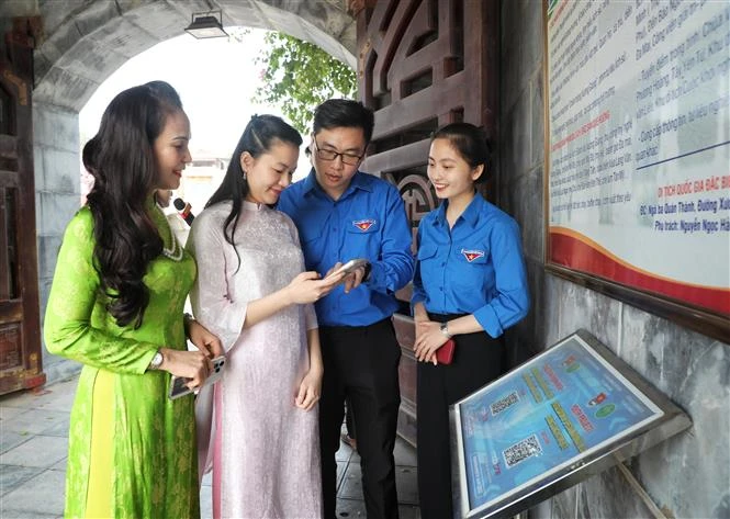 Youth Union members guide tourists to scan QR codes to learn about the Xuong Giang Victory historical site. (Photo: VNA)