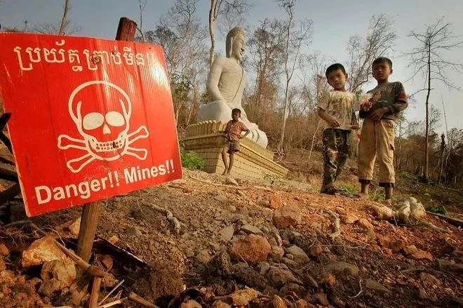 Children play near a landmine warning sign in the border area between Cambodia and Thailand. (Photo: AP)