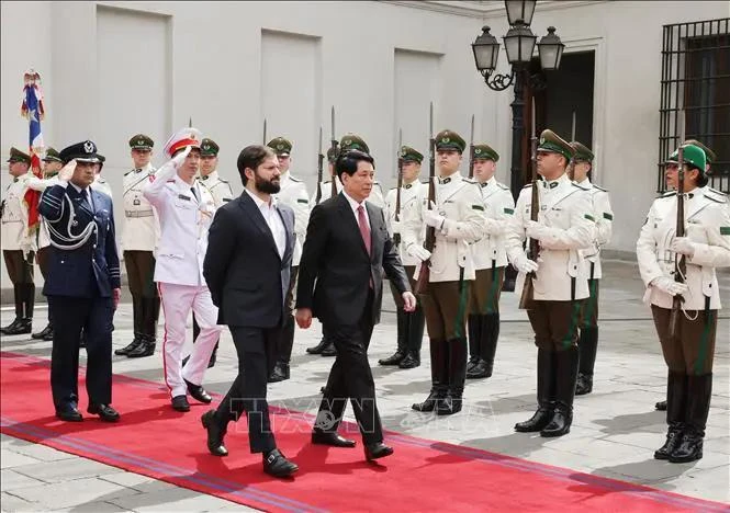 El presidente vietnamita, Luong Cuong (derecha), y su homólogo chileno, Gabriel Boric Font, pasan revista a la guardia de honor en Santiago. (Foto: VNA)