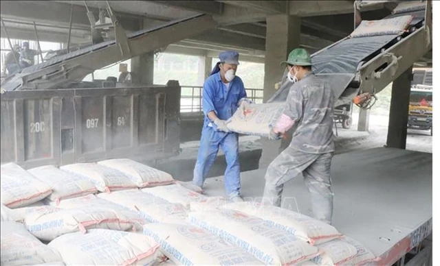 Des ouvriers chargent des sacs de ciment sur un camion dans une usine. (Photo : VNA)