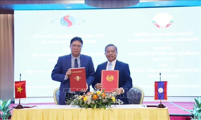 President of the Vietnam Academy of Science and Technology (VAST) Chau Van Minh (L) and Lao Minister of Technology and Communications Boviengkham Vongdara exchanges the minutes of cooperation. (Photo: VNA)