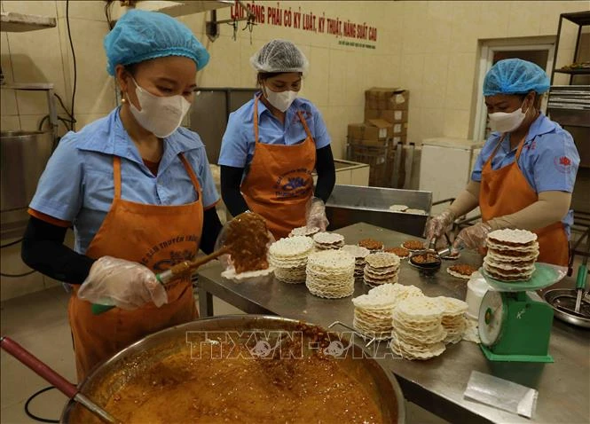 Workers make "cu do" - a candy made of roasted peanuts and molasses and covered with rice pancakes. The candy is a three-starred OCOP product of the central province of Ha Tinh. (Photo: VNA)