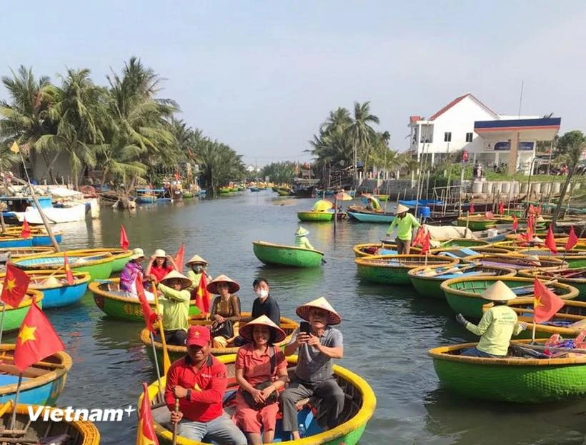 Tourists take a boat ride to explore the Bay Mau coconut forest. (Photo: VietnamPlus)