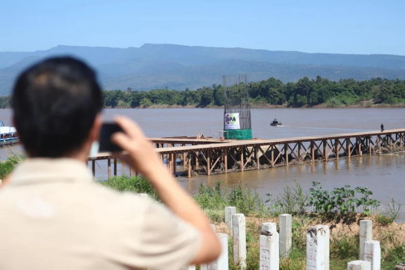 A visitor takes photos of the construction of the fifth Thai-Lao Friendship Bridge, between Bung Kan and Bolikhamxay, on October 28, 2022. The two countries have plans for another bridge, between Udon Ratchathani and Saravan. (Photo: bangkokpost.com)