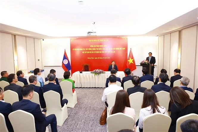 Prime Minister Pham Minh Chinh (standing) speaks at the meeting with staff of the Vietnamese Embassy and Vietnamese representative agencies in Laos on October 8. (Photo: VNA)