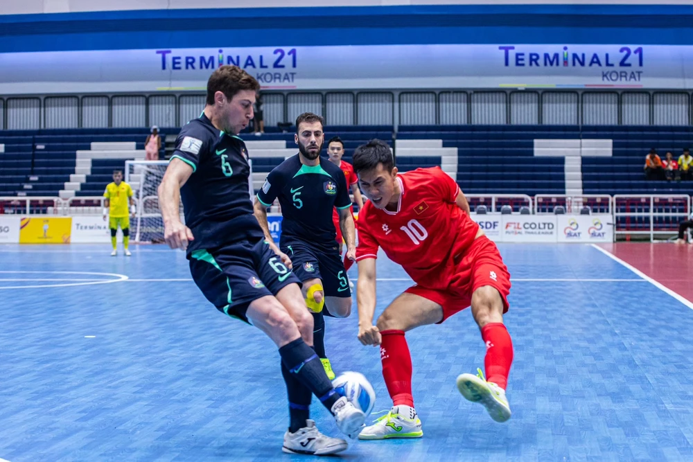 A Vietnamese futsal player (red) faces two Australian players at the semi-final match of the ASEAN Futsal Championship 2024 on November 8. (Photo: VNA)