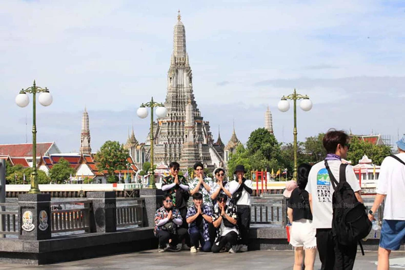 Tourists pose for pictures at the Tha Tien pier by the Chao Phraya River opposite the Temple of Dawn (Wat Arun) in Bangkok in June. (Photo: Bangkokpost)