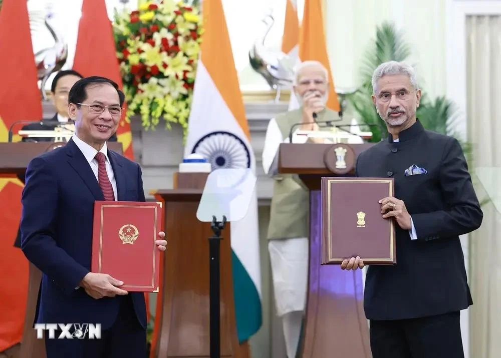 Leaders of the foreign ministries of Vietnam and India exchange an agreement between their governments allowing family members of diplomatic and consular staff to work for income. (Photo: VNA)