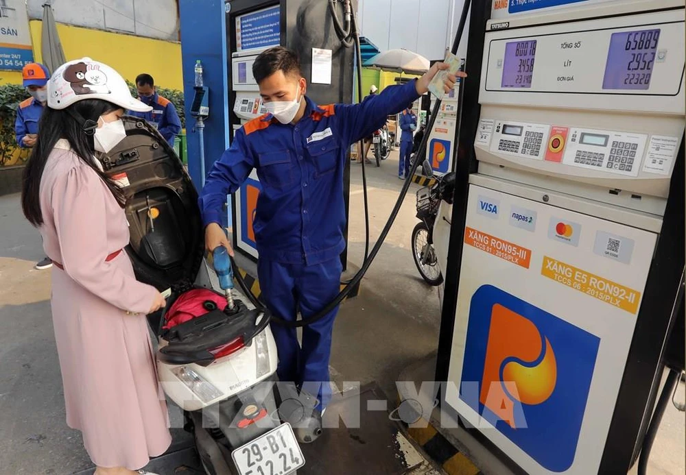 A customer buys petrol at a petrol station in Hanoi. The retail prices of E5RON92 bio-fuel and all petrol products decrease from 3pm on July 11 (Photo: VNA)