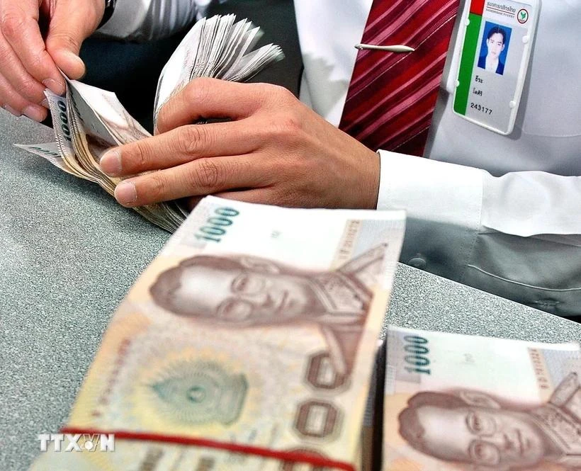 A bank employee counts baht in Bangkok, Thailand. (Photo: AFP/VNA)