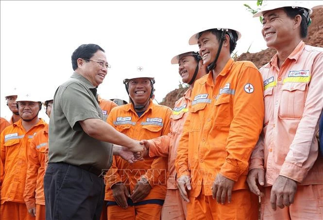 Le Premier ministre Pham Minh Chinh et des ouvriers sur le chantier. Photo: VNA