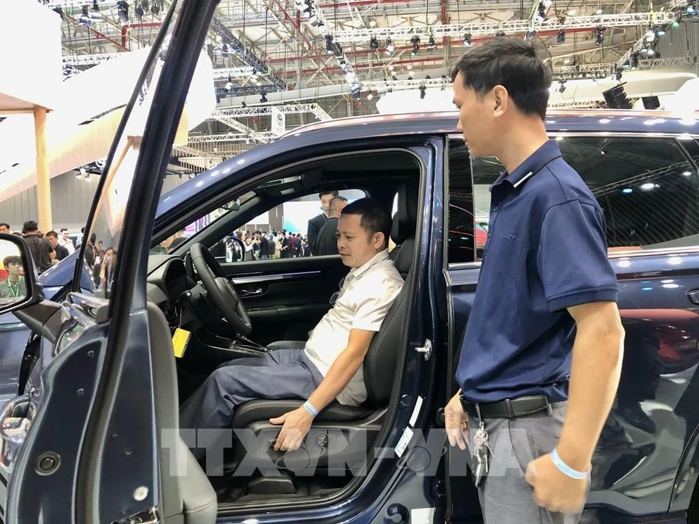 Un visiteur découvre un modèle de voiture avec de nouvelles technologies lors de l'exposition. Photo: VNA