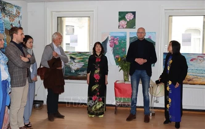 旅居比利时越南女画家金团和代表们在“爱之土地”的画展开幕式上。图自越通社