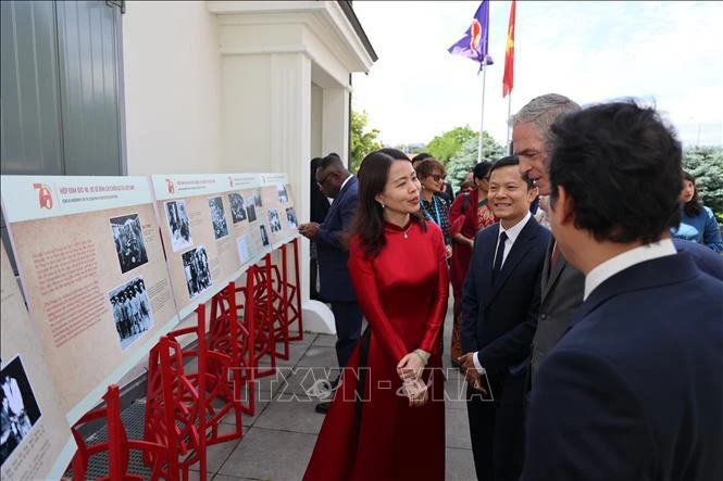 越南外交部副部长阮明恒向国际友人介绍此展上的图片。图自越通社
