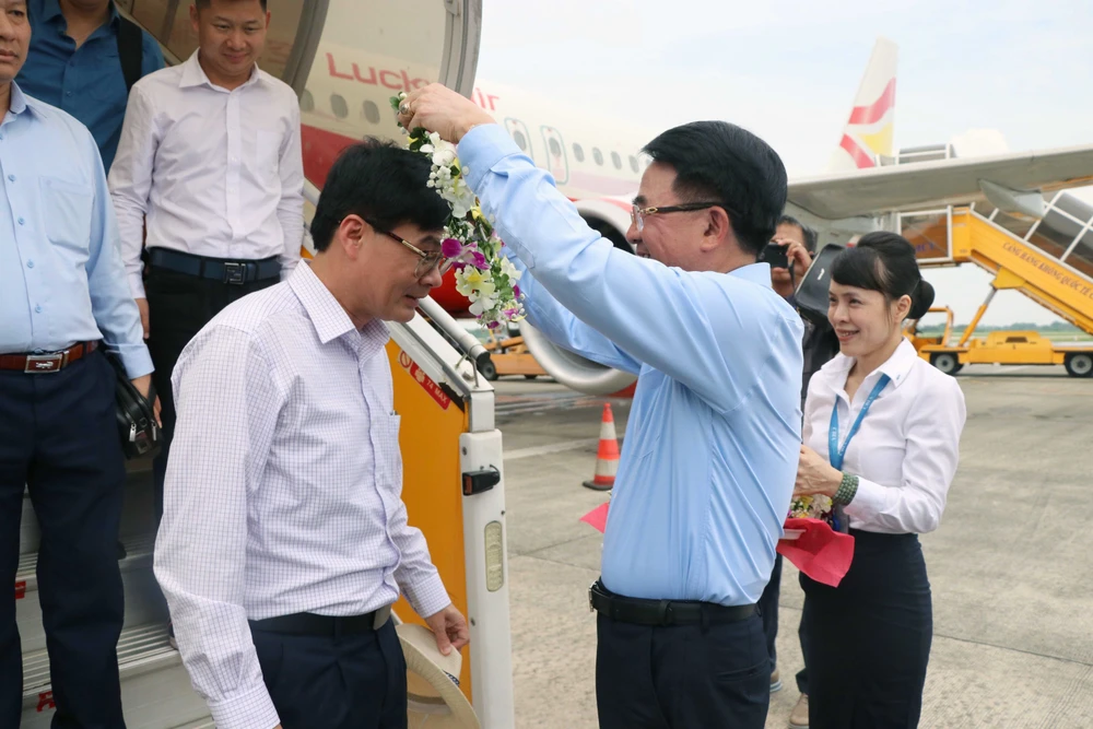 海防市人民委员会副主席黎克南向从中国云南省丽江起飞的首个航班的乘客送花。图自越通社