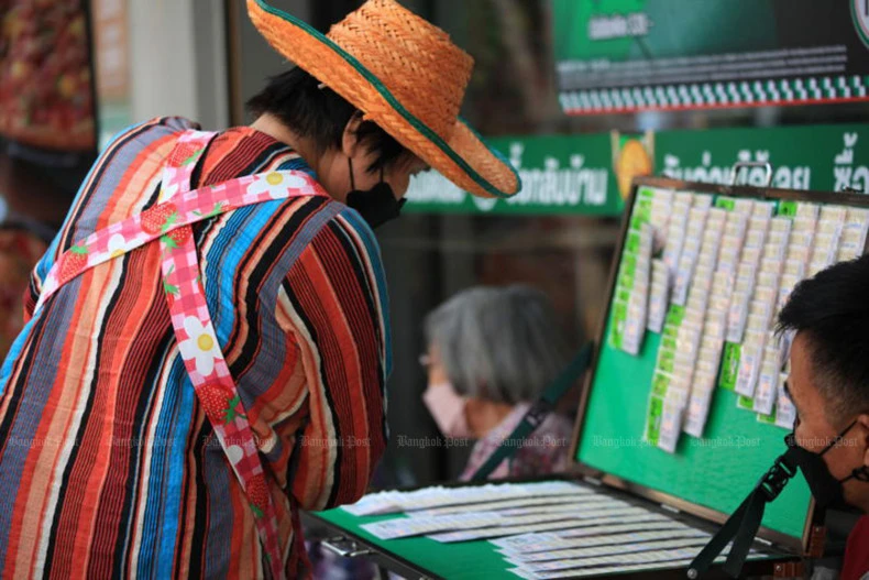 A woman looks for lottery tickets with numbers she favours at a stall in Phra Nakhon district, Bangkok. (Photo: bangkokpost.com) 