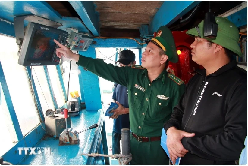 A border guard officer checks monitoring devices on a fishing vessel (Photo: VNA) 