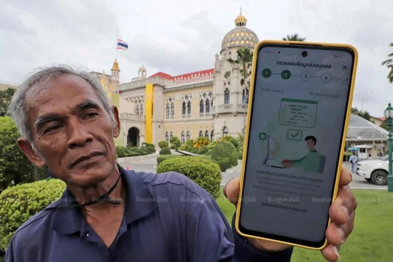 Un jardinero tailandés muestra un mensaje en su teléfono en respuesta a su registro en el sistema de billetera digital. (Foto: bangkokpost.com)